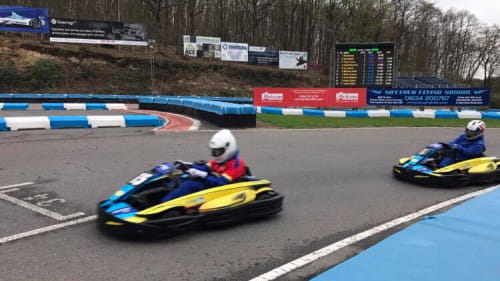 Side photo of two Karts going round a track corner